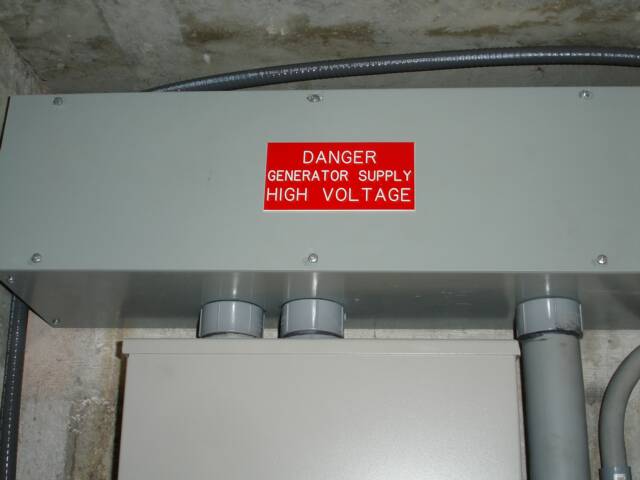 Generator Installation, Inside shot with neatly mounted pipes and wiring. Sign says DANGER GENERATOR SUPPLY HIGH VOLTAGE