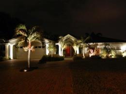 Landscape Lighting. Residential home front view with nicely lit trees, plants, and home at night.